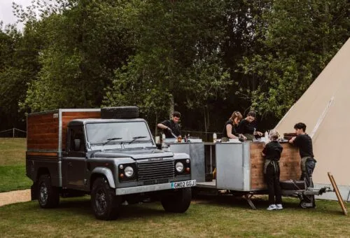 The Wild Oven Defender set up beside a tipi — the reference for this model; linked only.